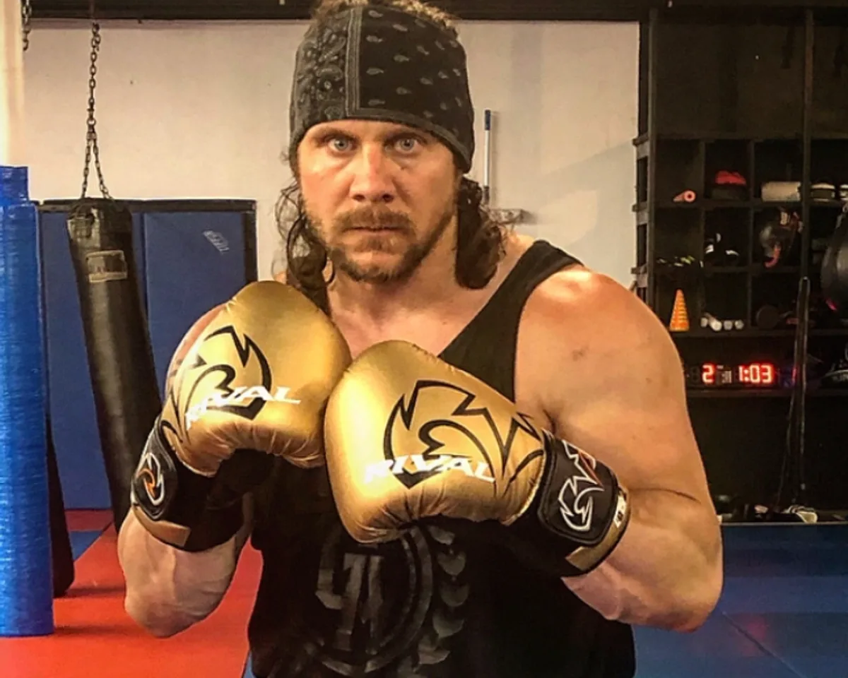 Iron Mike, head coach and founder of Furst Place MMA, in a boxing stance with gold gloves up in the gym