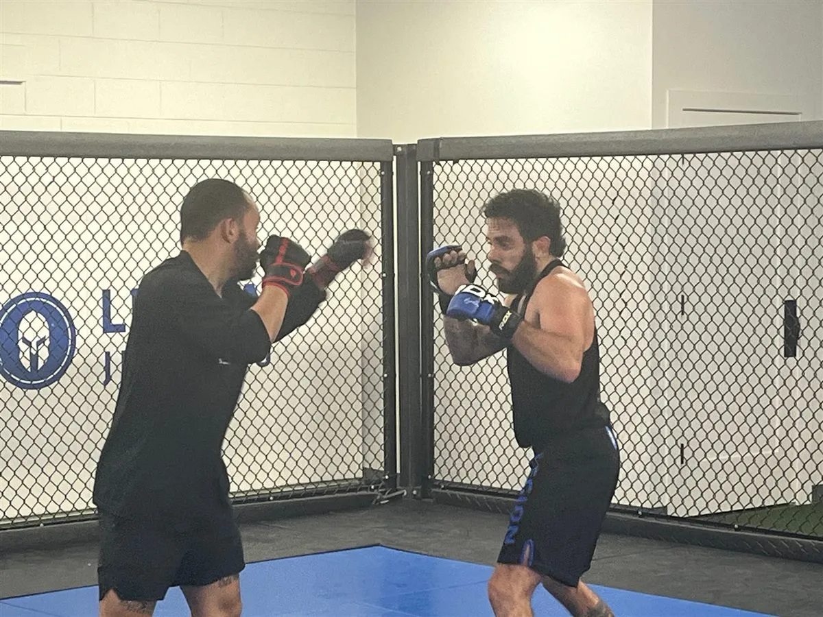 Two members sparring with gloves up by the cage at Furst Place MMA